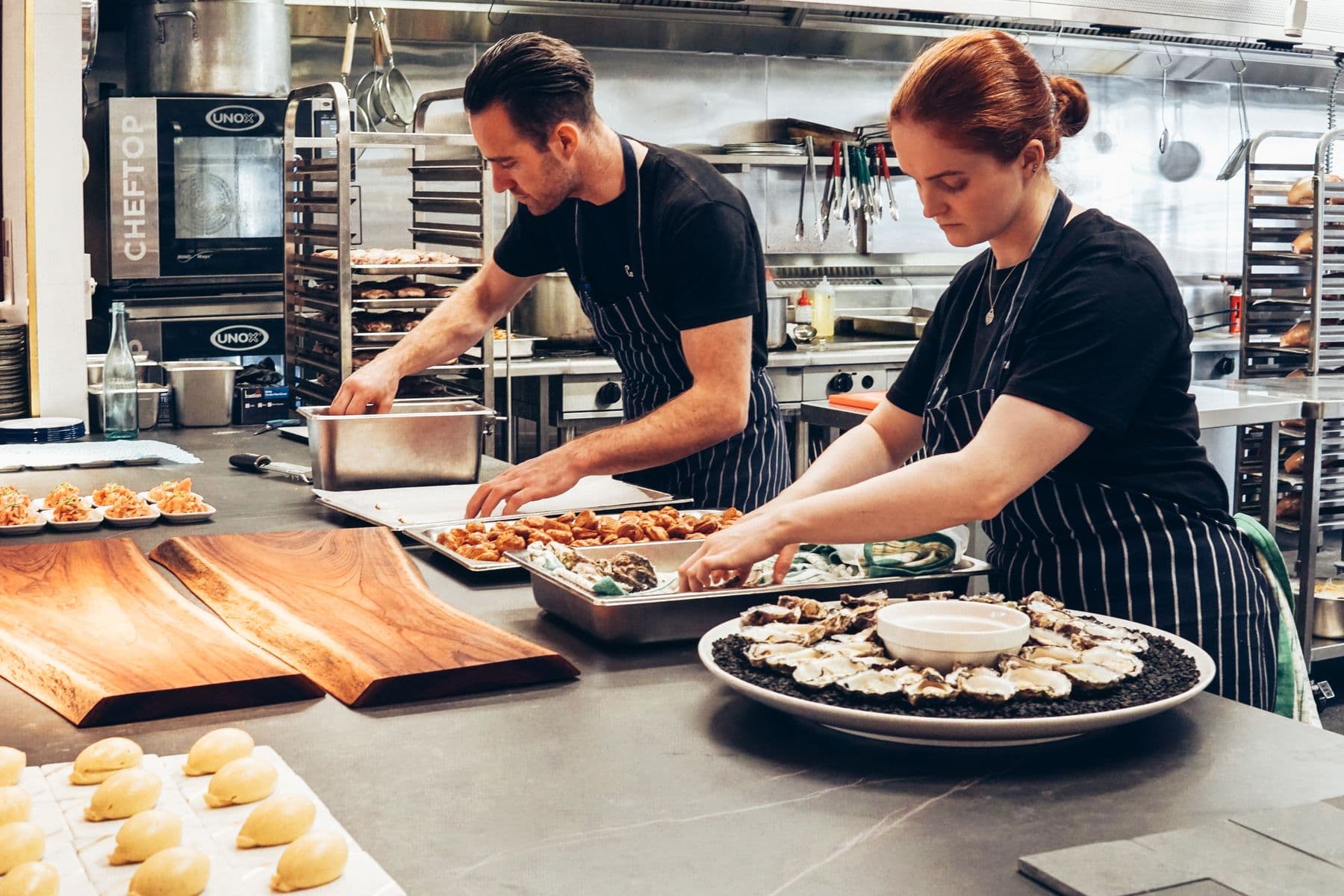 Deux cuisiniers dressent des plats en cuisine.