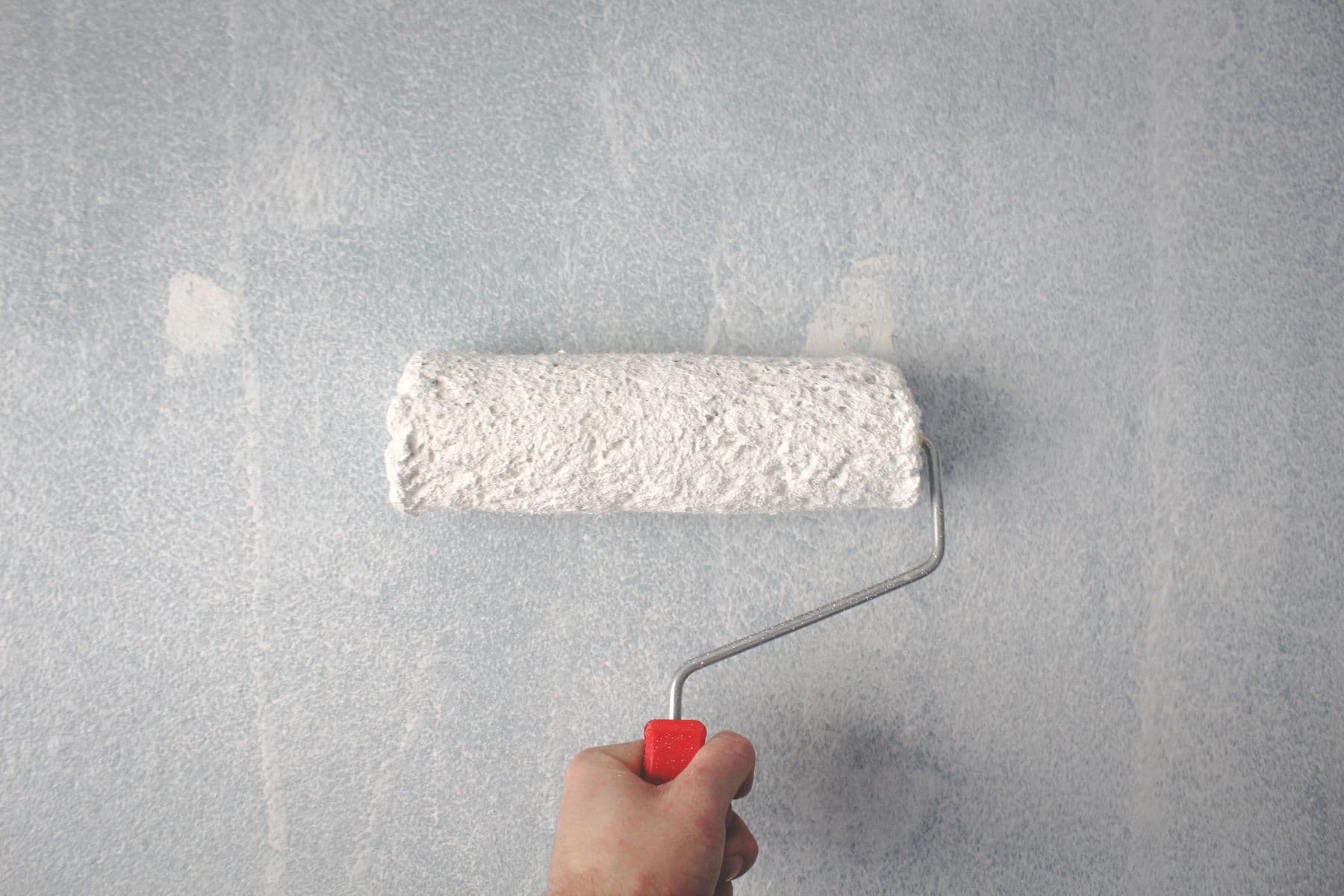 Rouleau de peinture blanche sur un mur.