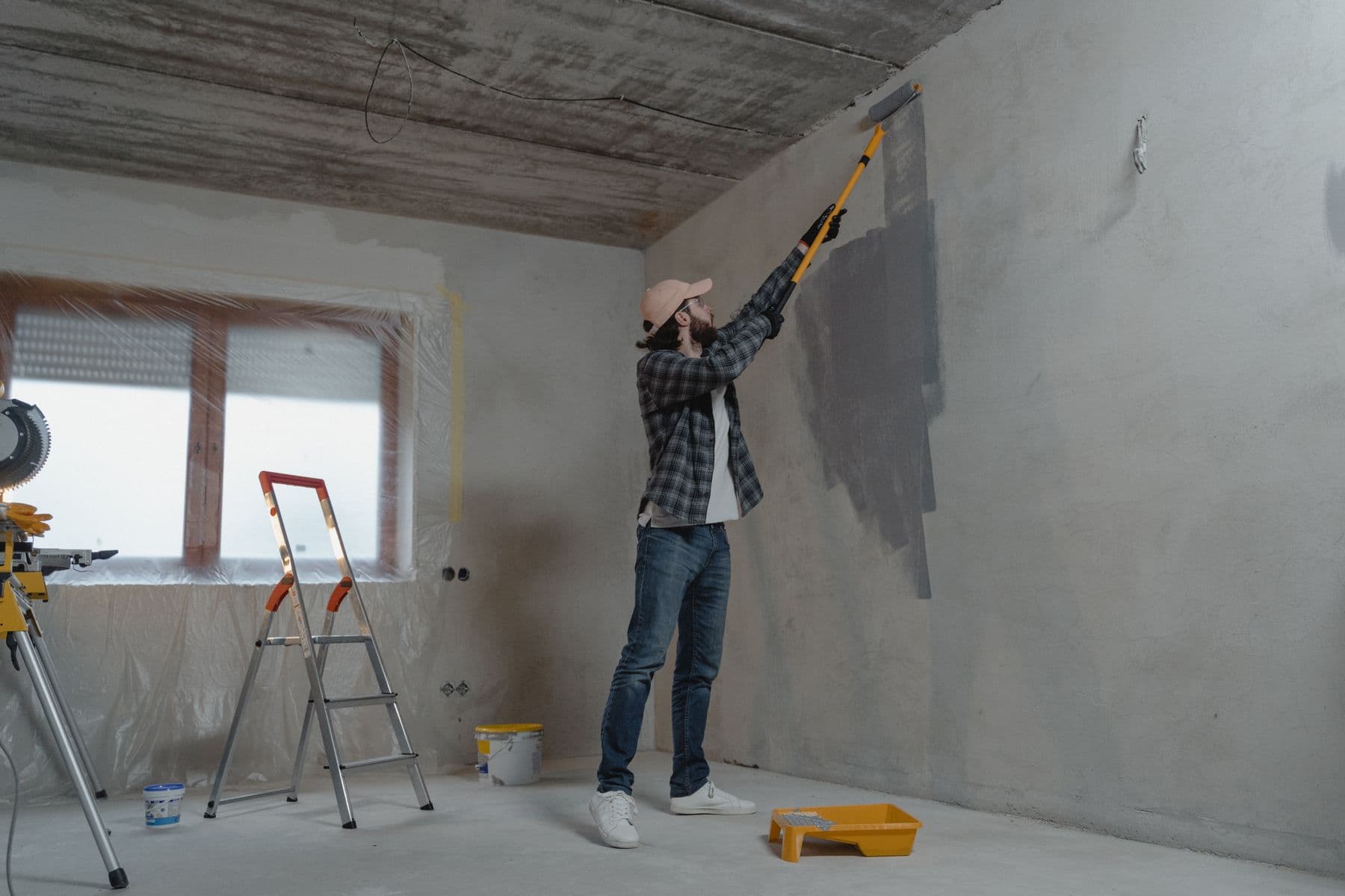 Peintre au rouleau dans une pièce en travaux.